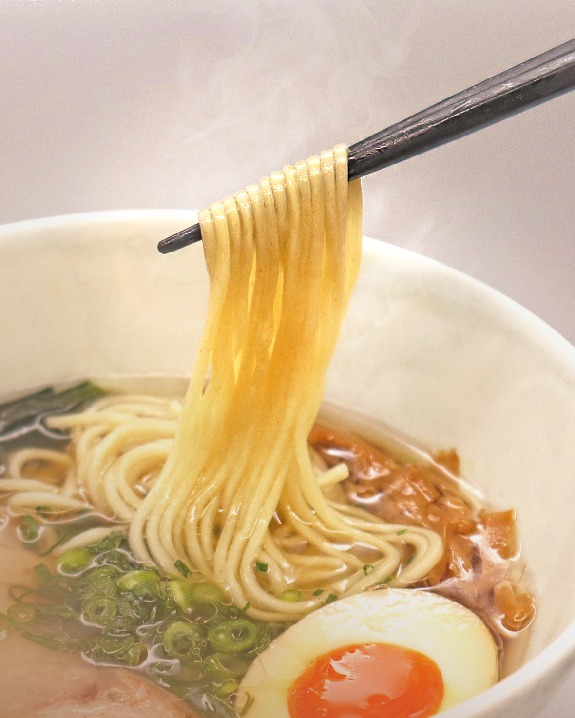 ラーメンを箸で上げている写真