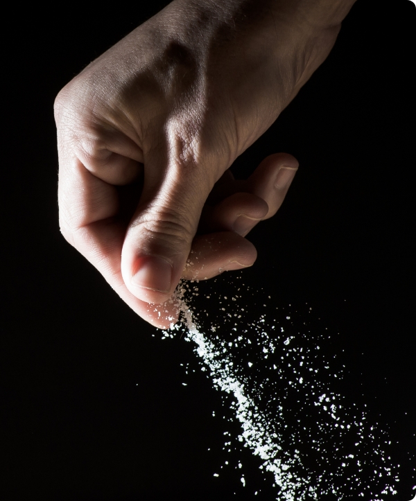 つまんだ塩を振りかけている様子の写真